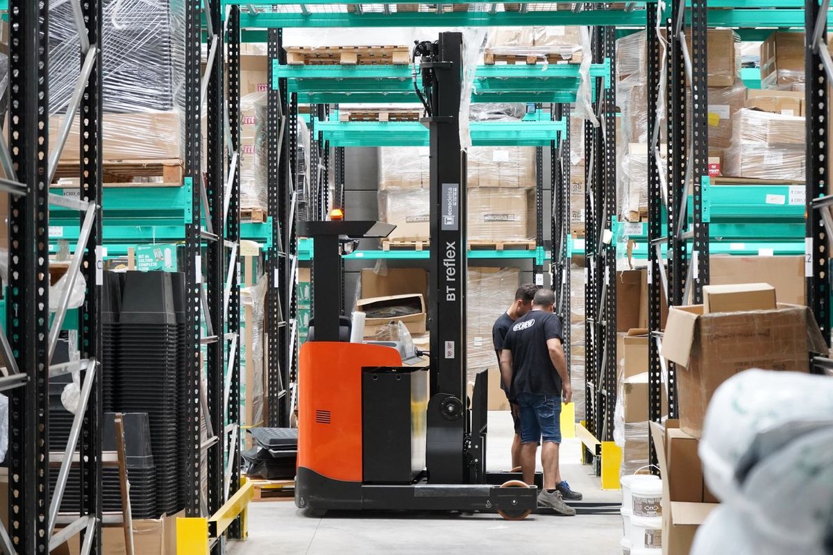 Full electric pallet stacker in a warehouse aisle